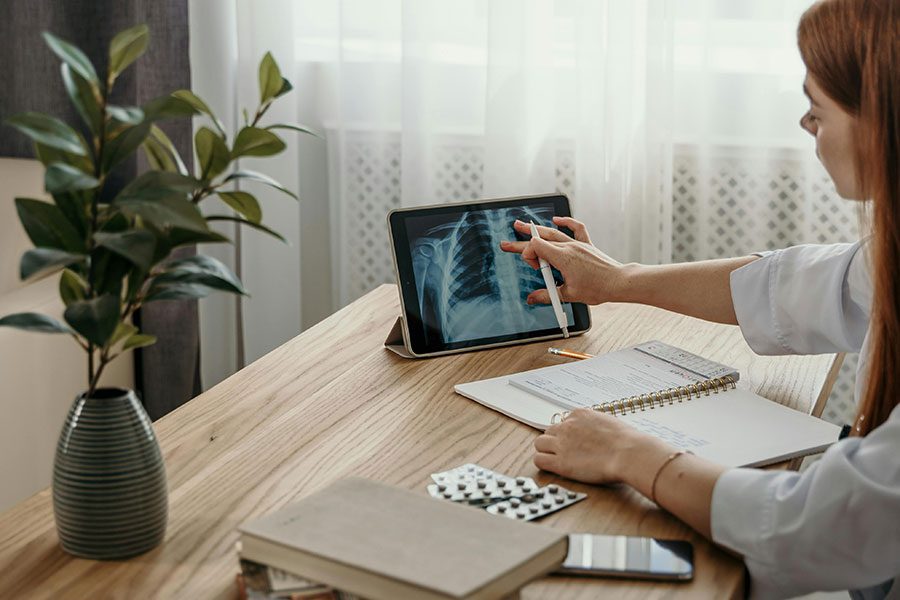 A doctor looking at an image scan of ribs a tablet